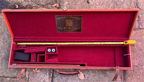 A BRASS CORNERED LEATHER GUN CASE WITH HOLLAND & HOLLAND TRADE LABEL